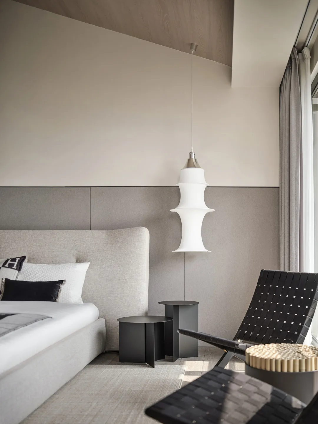 Modern minimalist bedroom featuring fabric upholstered furniture, metal accents, and glass pendant light hanging from the cei