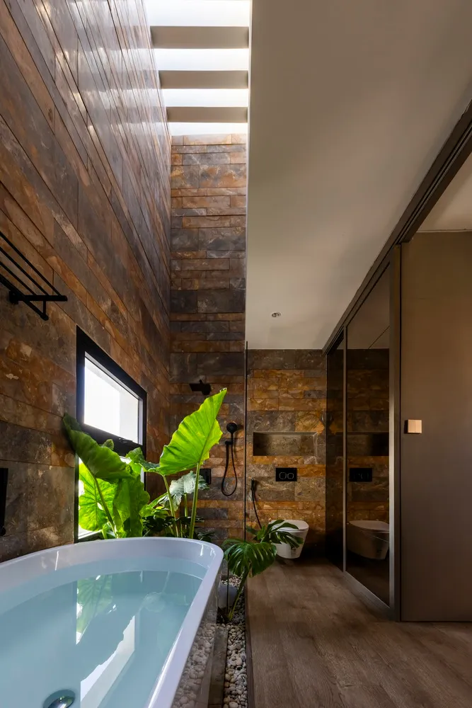 A modern bathroom features a bathtub, plants, and wooden materials.