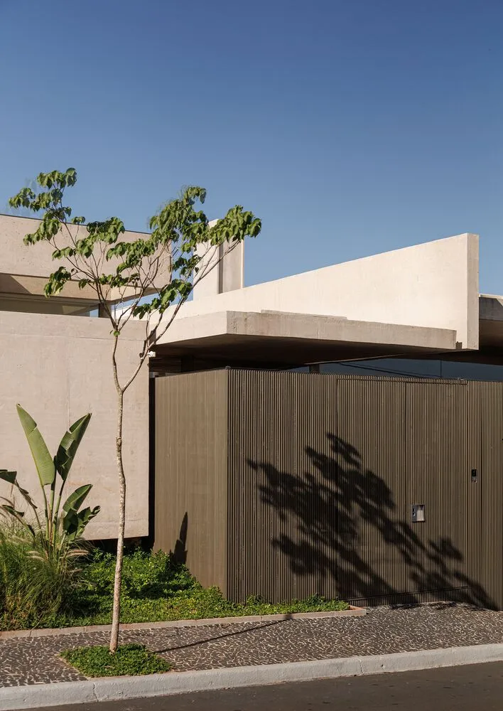 A modern building exterior with a concrete facade and a green tree in the foreground.