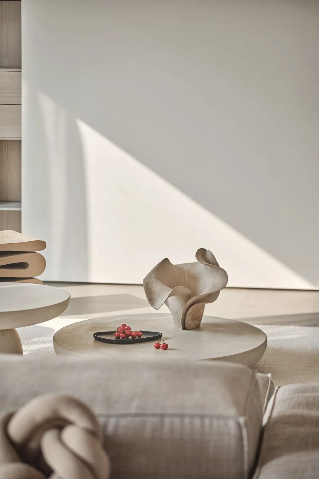 A modern, minimalist coffee table setting made of concrete with a decorative vase and cherries.