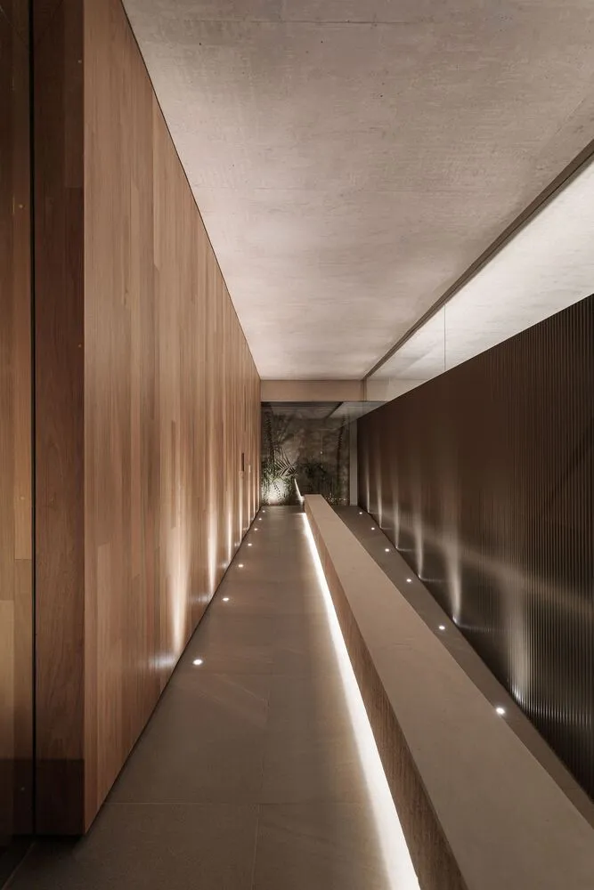 A modern, minimalist corridor with wooden walls and recessed lighting.