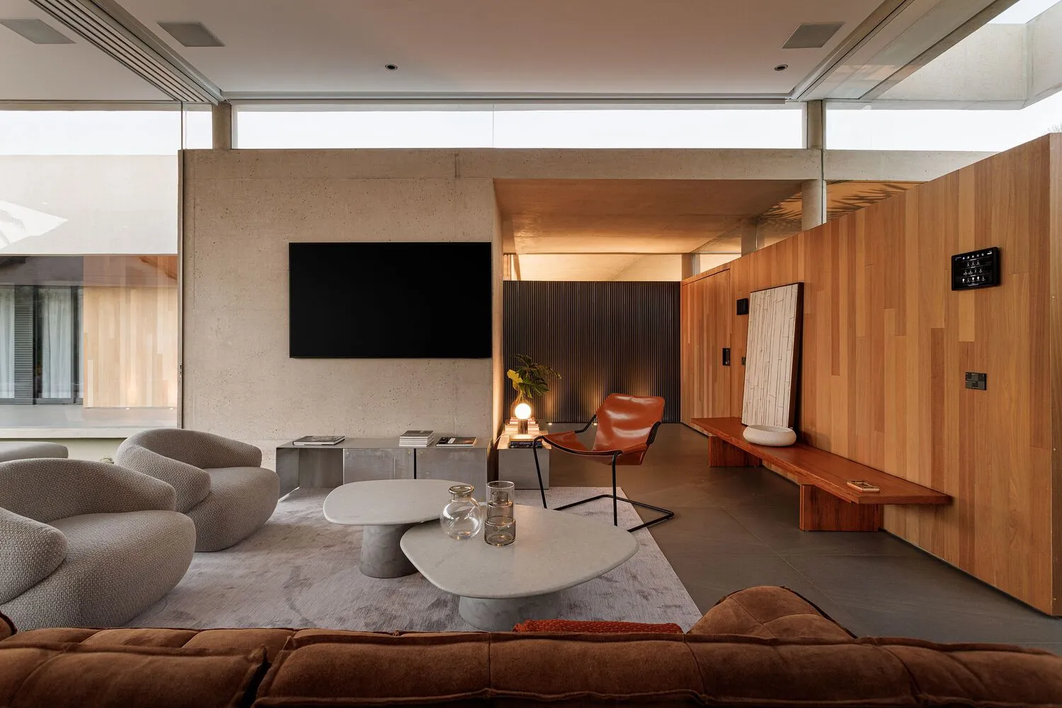 A modern living room featuring concrete walls, wooden accents, and marble coffee tables.