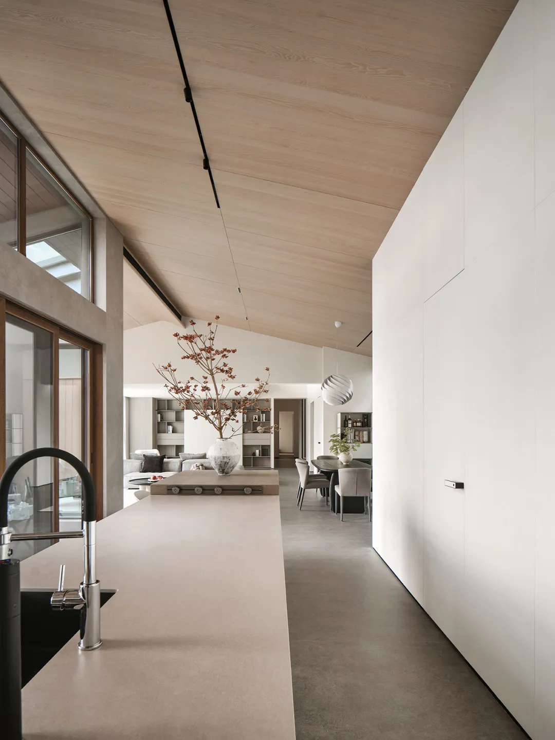 A modern minimalist kitchen with concrete walls, a wooden island, and a large window providing natural light.