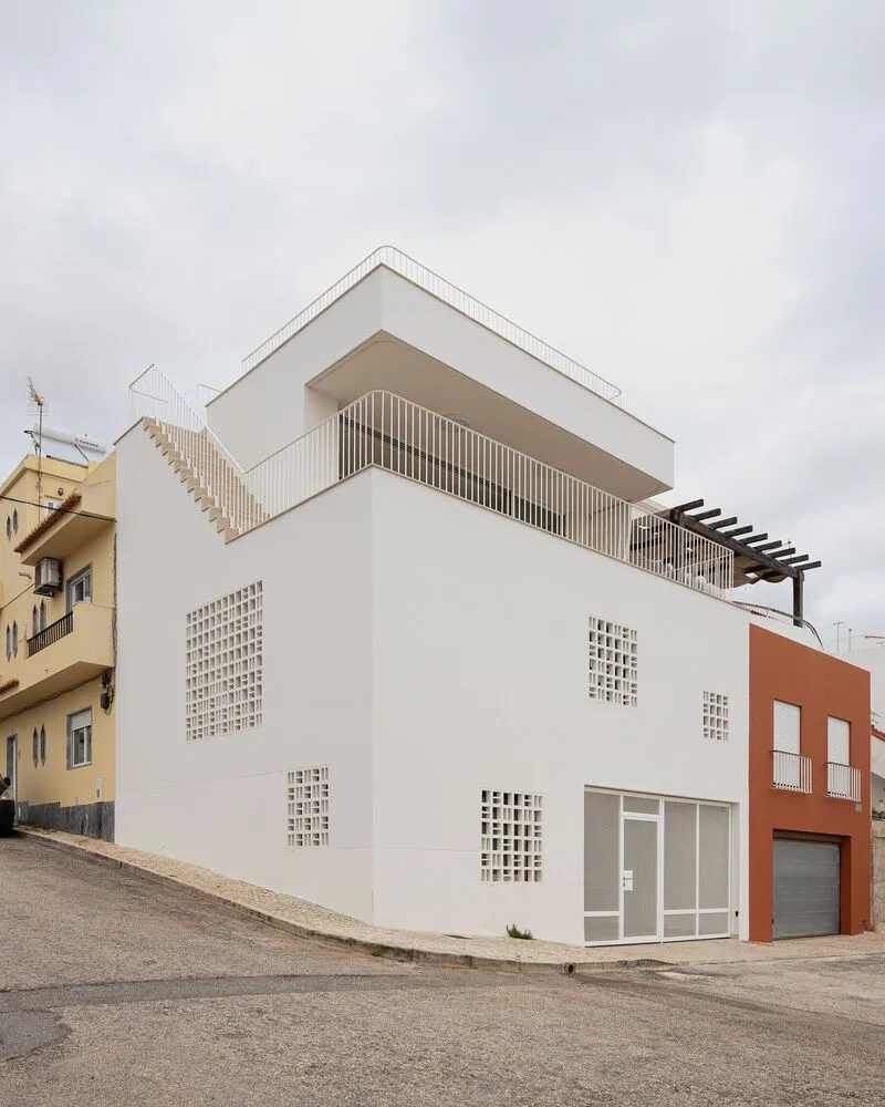 A modern residential building with concrete and glass features a rooftop staircase and a private balcony.