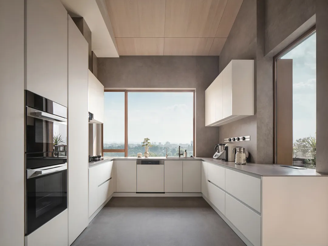 Contemporary kitchen with white cabinets and counter, modern appliances, and large windows overlooking scenic view.