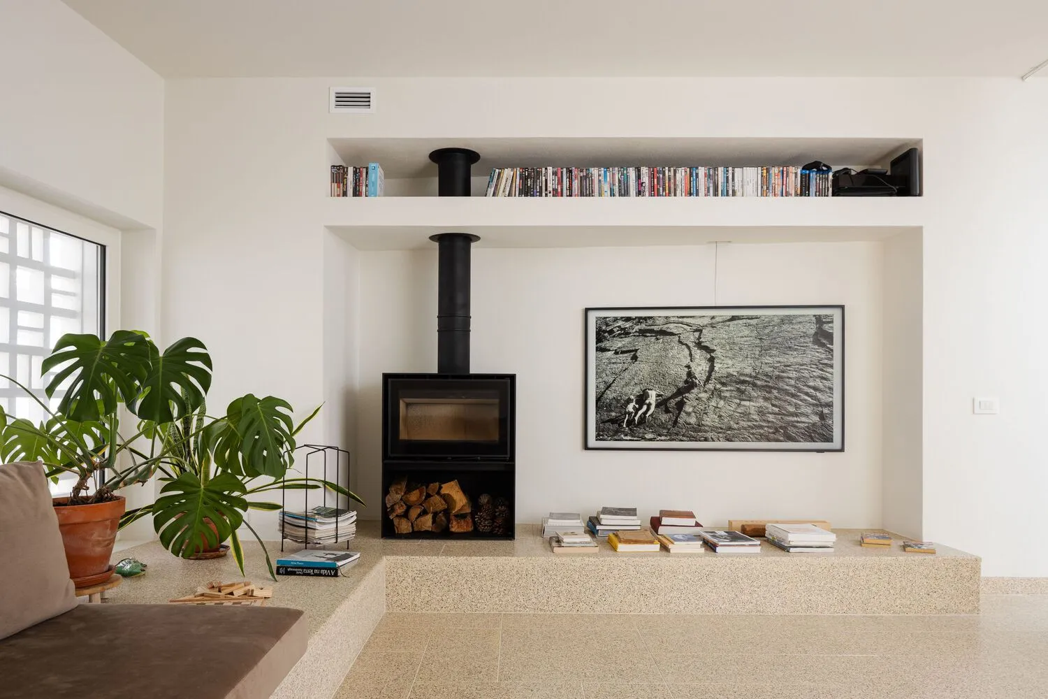 A minimalist living room featuring concrete elements and a modern fireplace.
