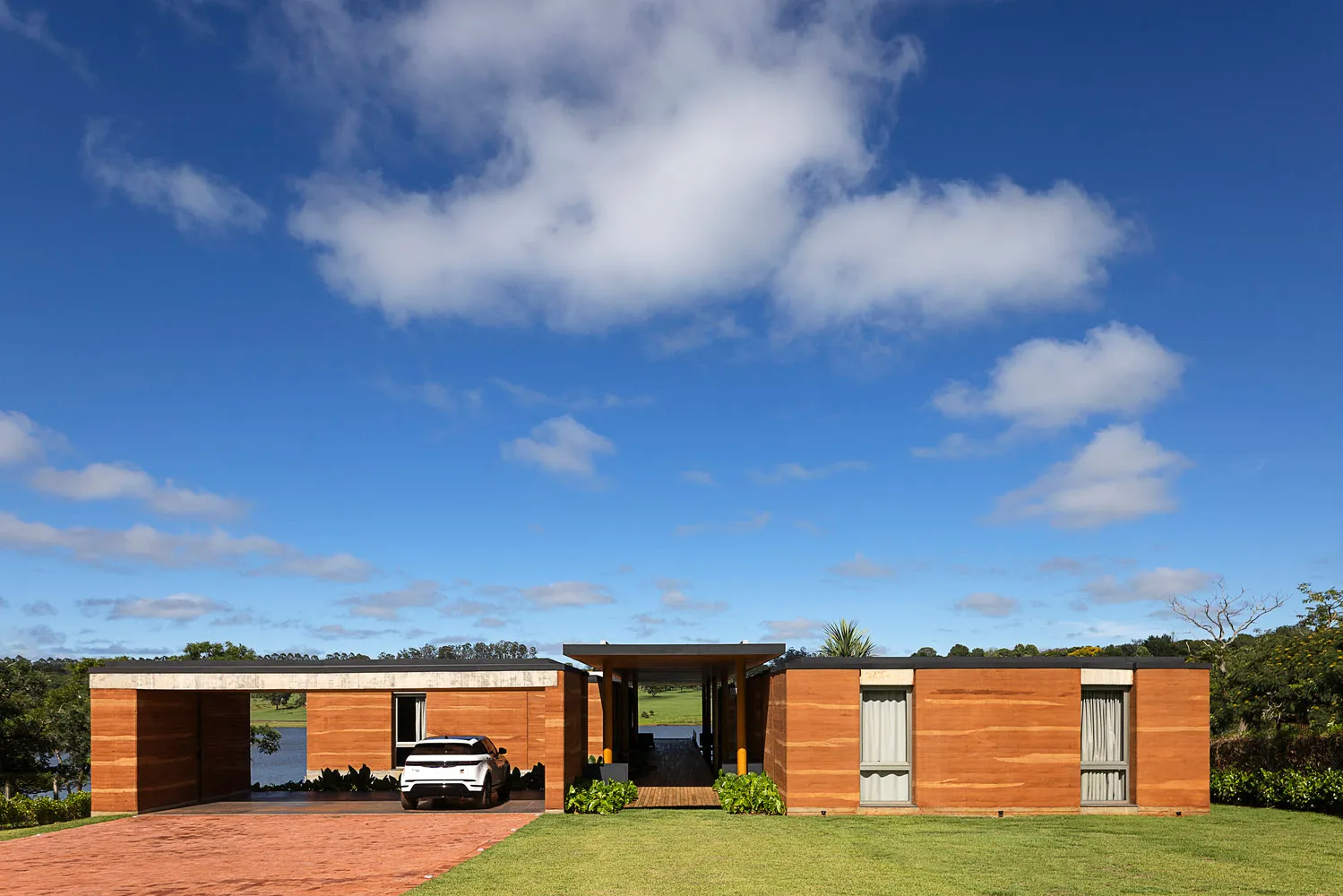A modern residential building with a wooden exterior and a car parked in the driveway.