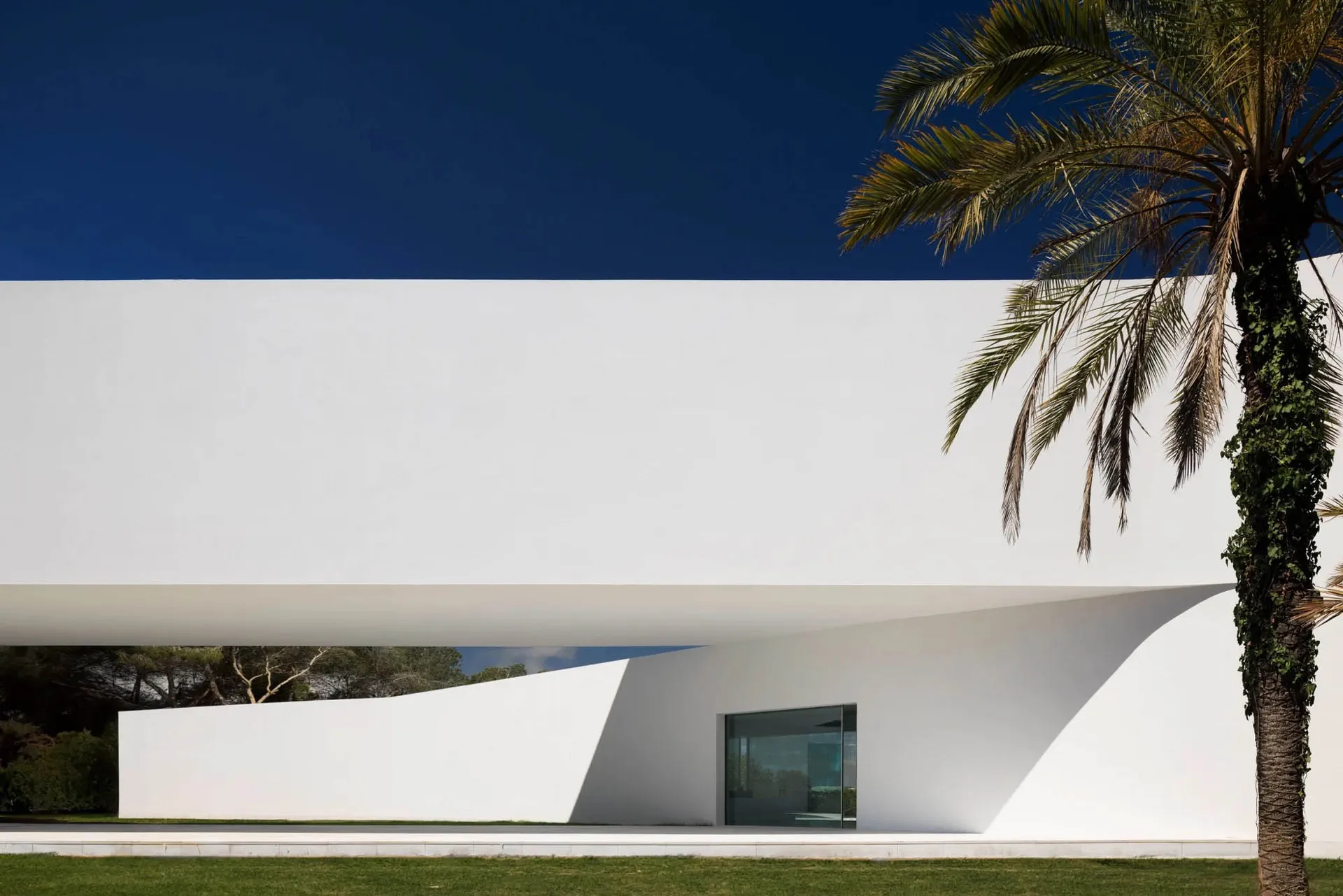 A modern house with a white concrete exterior and minimalist design.