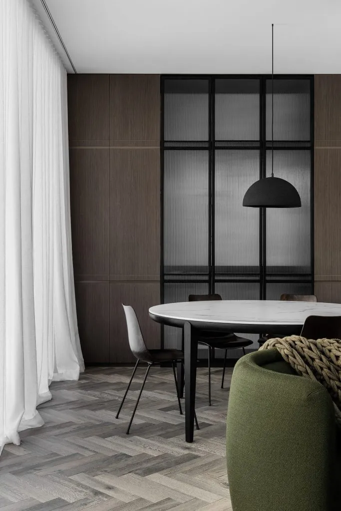 Minimalist dining room featuring a marble dining table, modern chairs, and a pendant light.