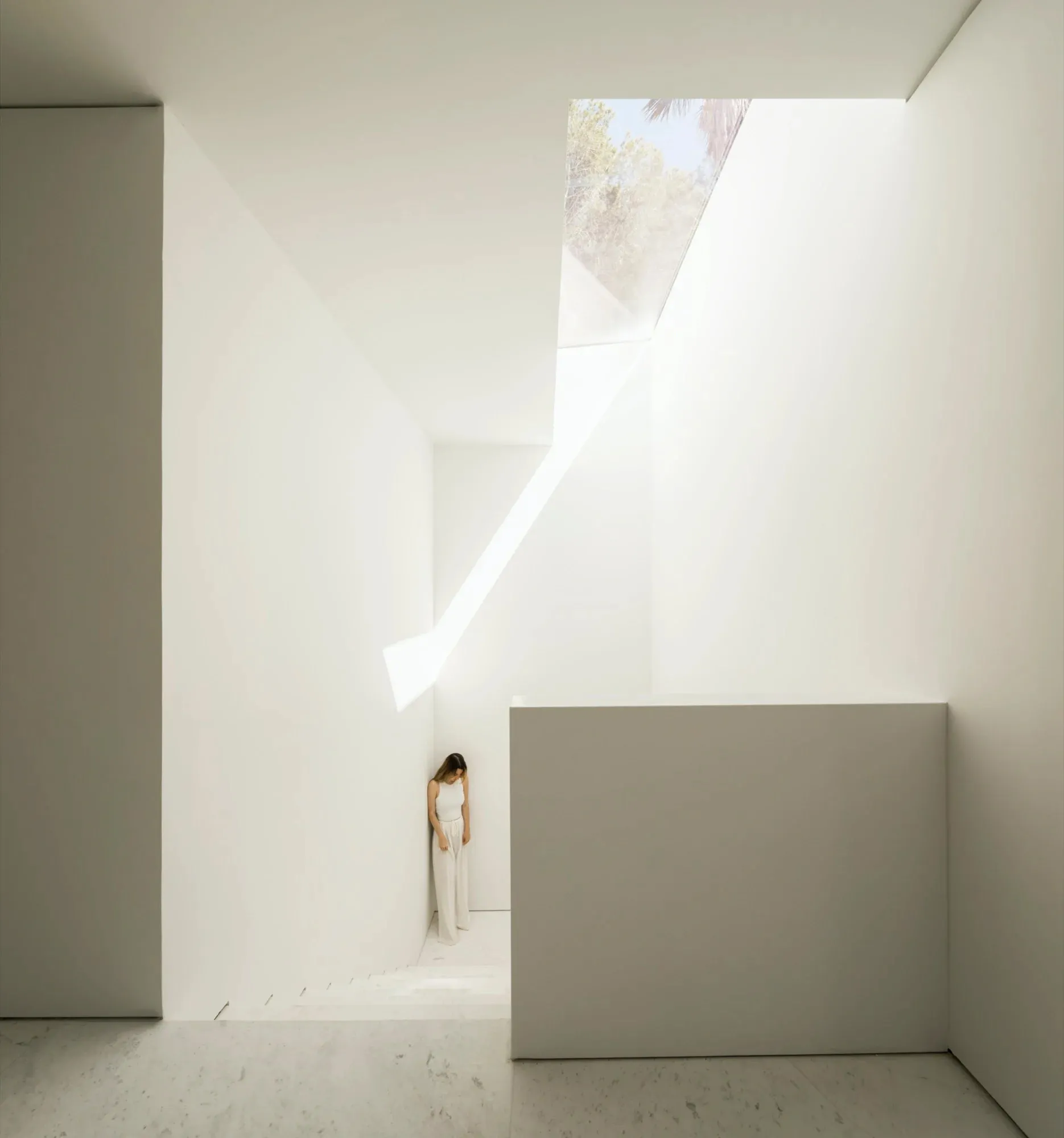 A minimalist interior space with a marble floor and concrete walls.