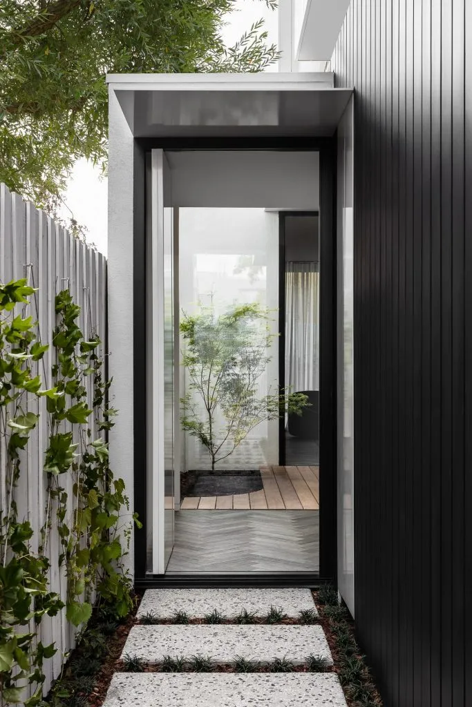 A modern entryway featuring a glass and metallic black door.