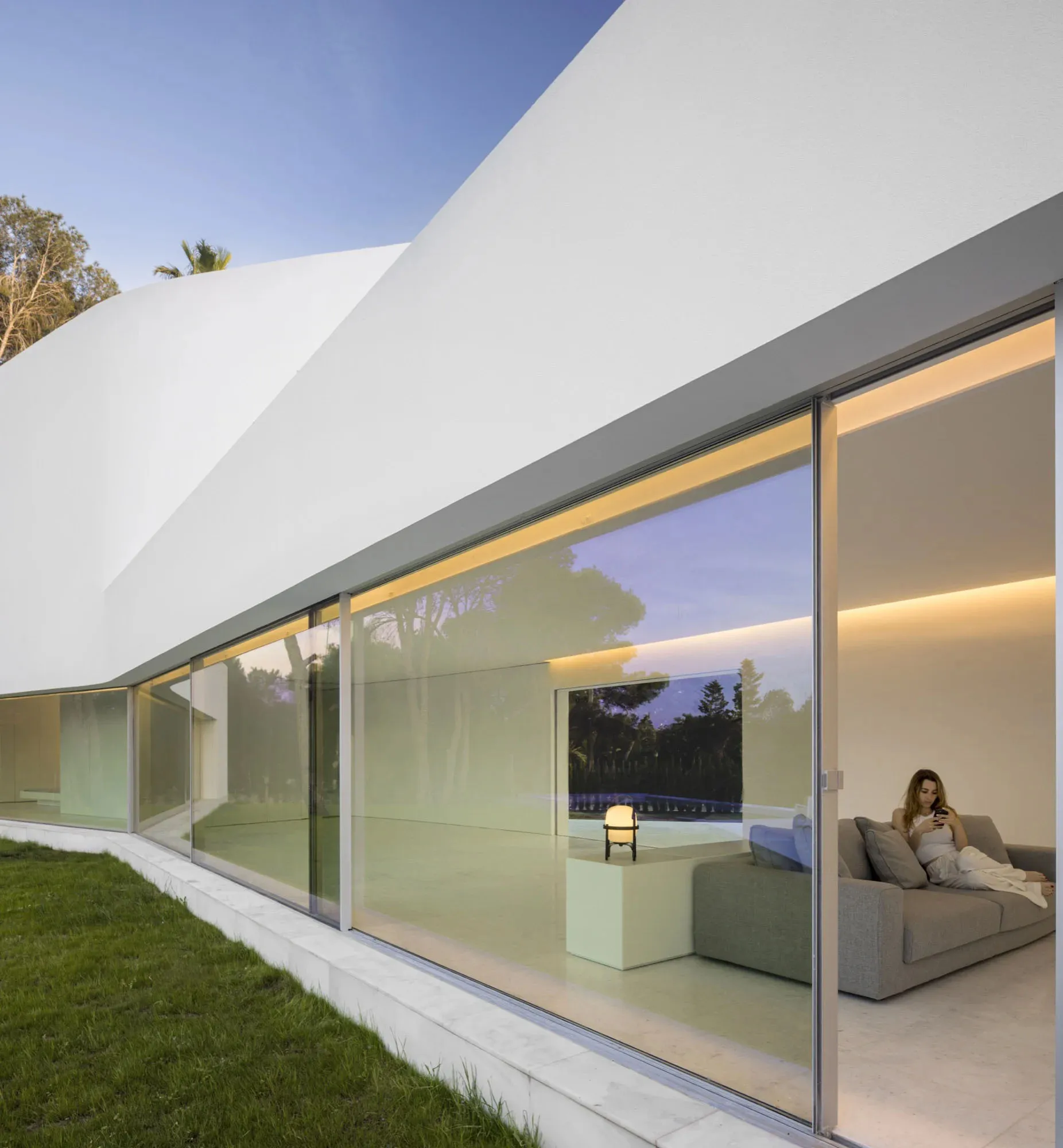 A modern house featuring glass windows and a terrace overlooking trees.