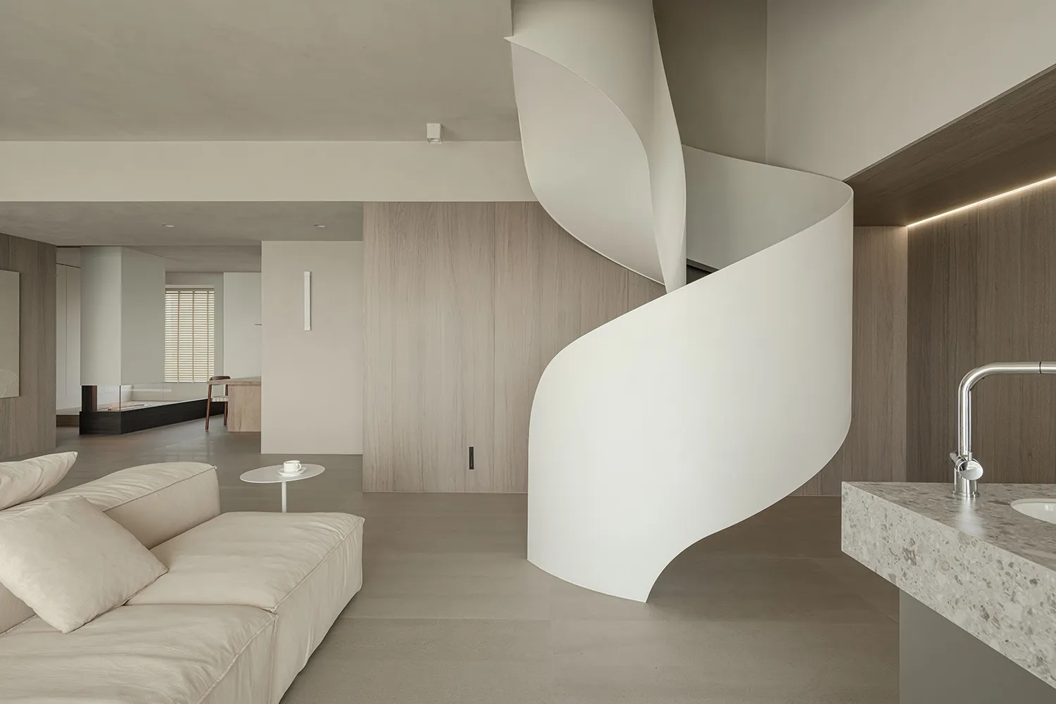 A modern living space featuring neutral-toned walls, flooring, and furniture.