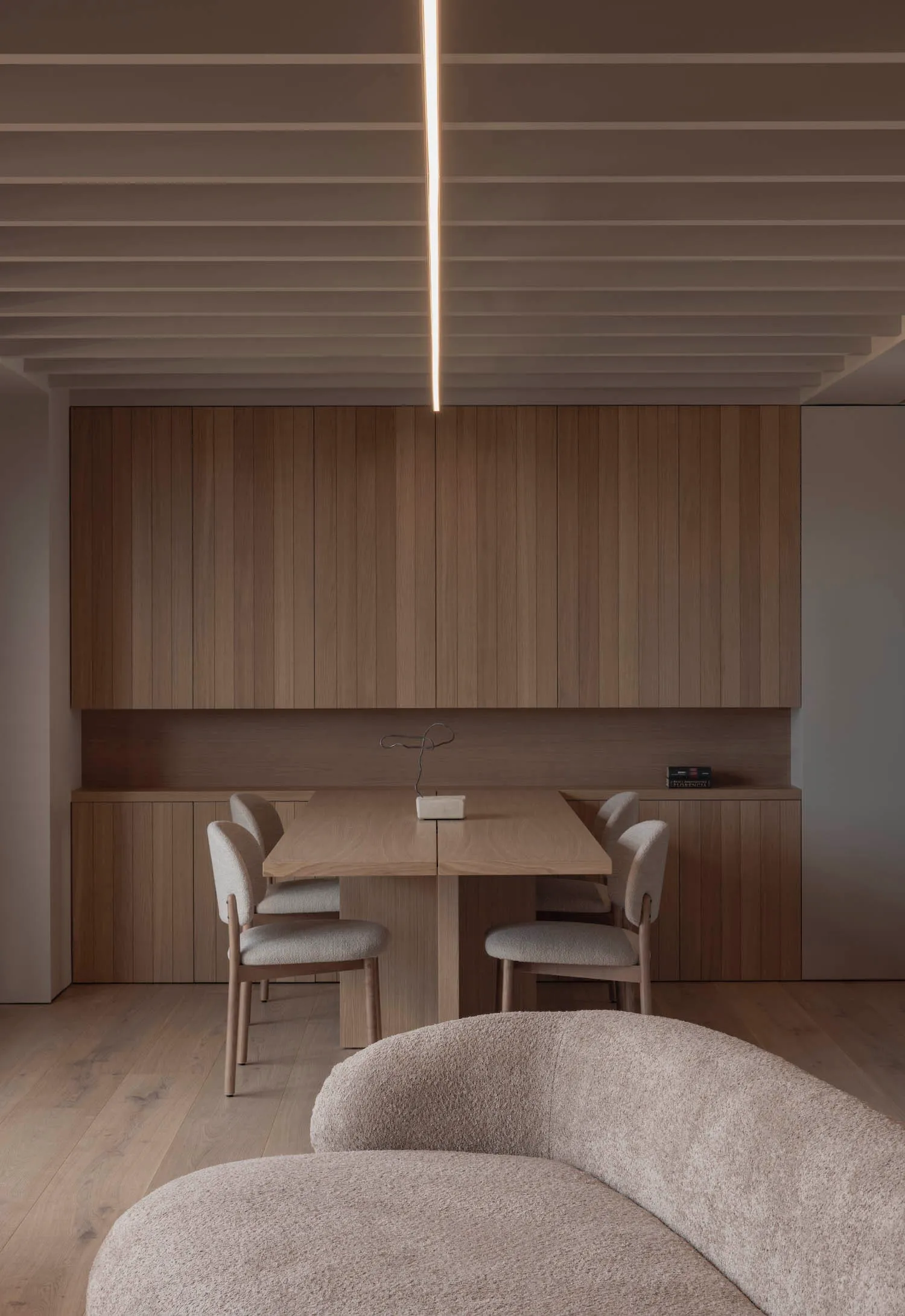 A minimalist residential dining room featuring wooden furniture and a sleek table with chairs.