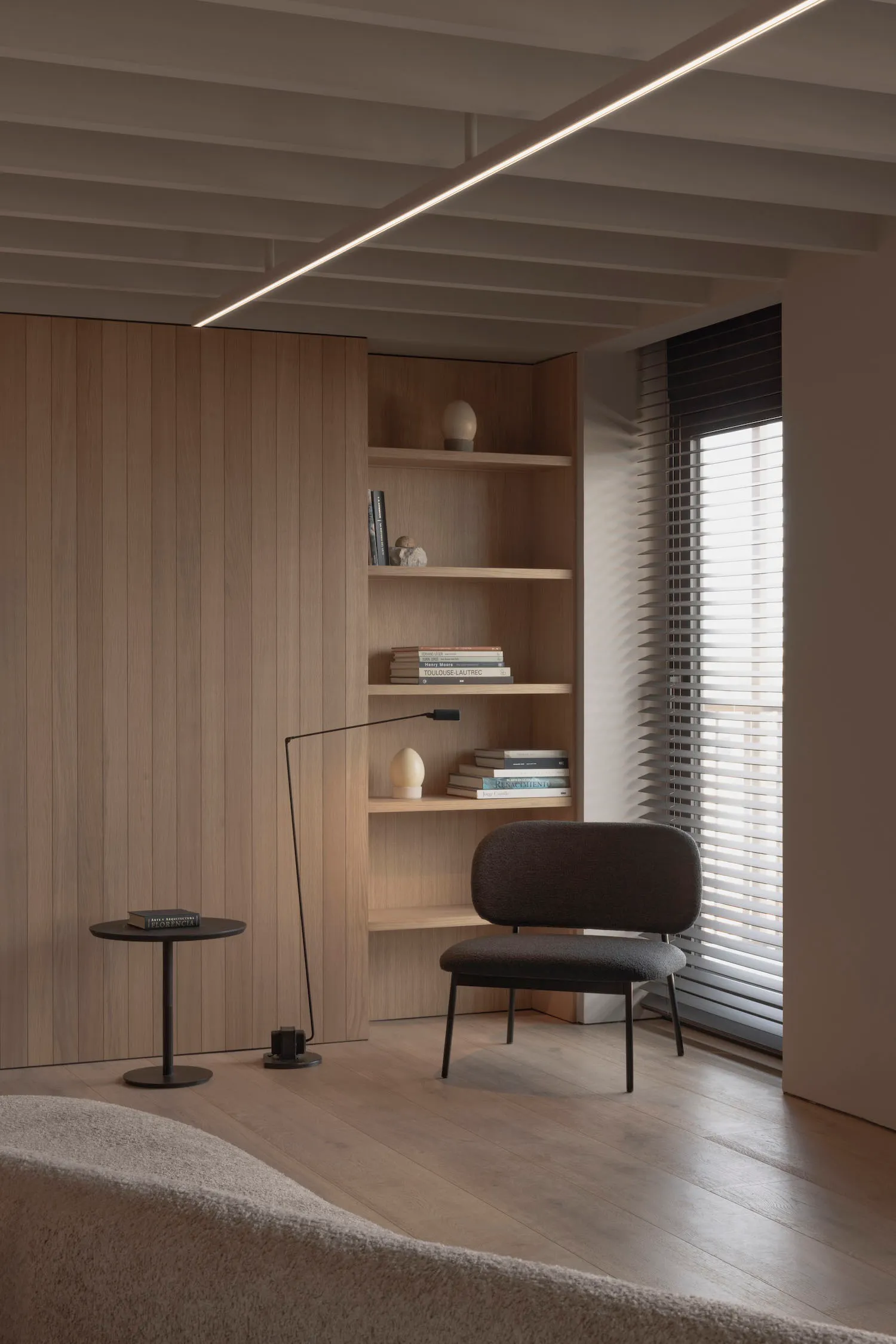 A modern living room featuring a wooden wall, shelves, and a chair.