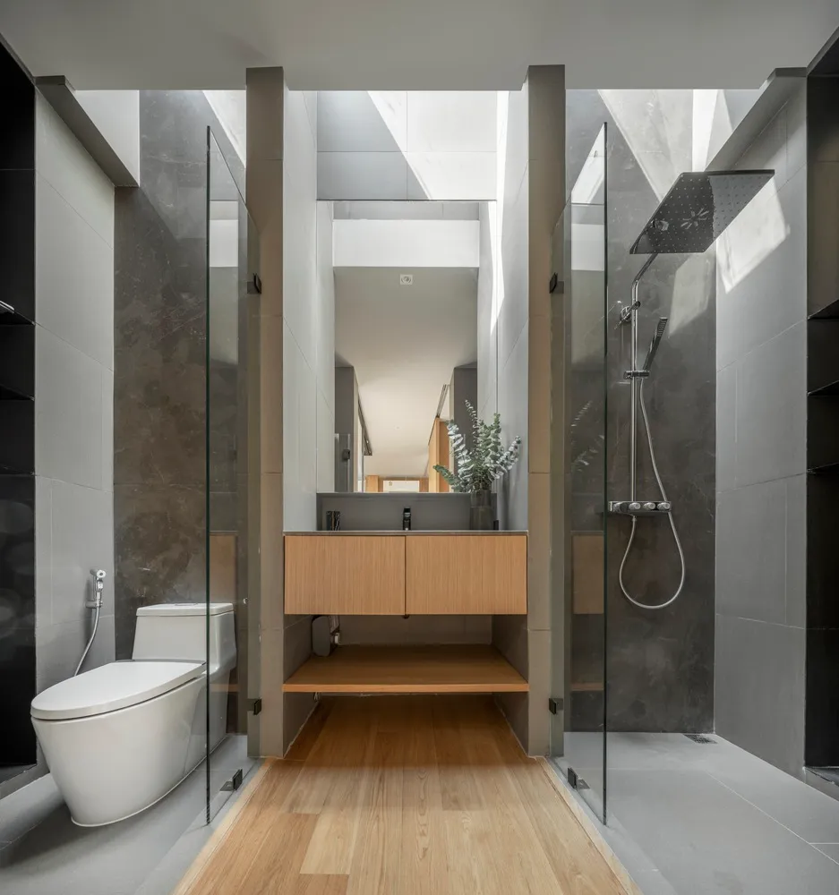 Modern bathroom with concrete walls and floors, featuring a sleek sink, toilet, and shower with wooden accents.
