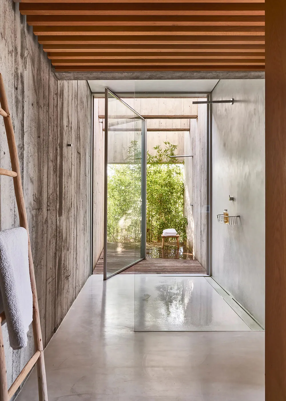 Modern bathroom with minimalist design featuring concrete walls and a glass door leading to an outdoor patio area.