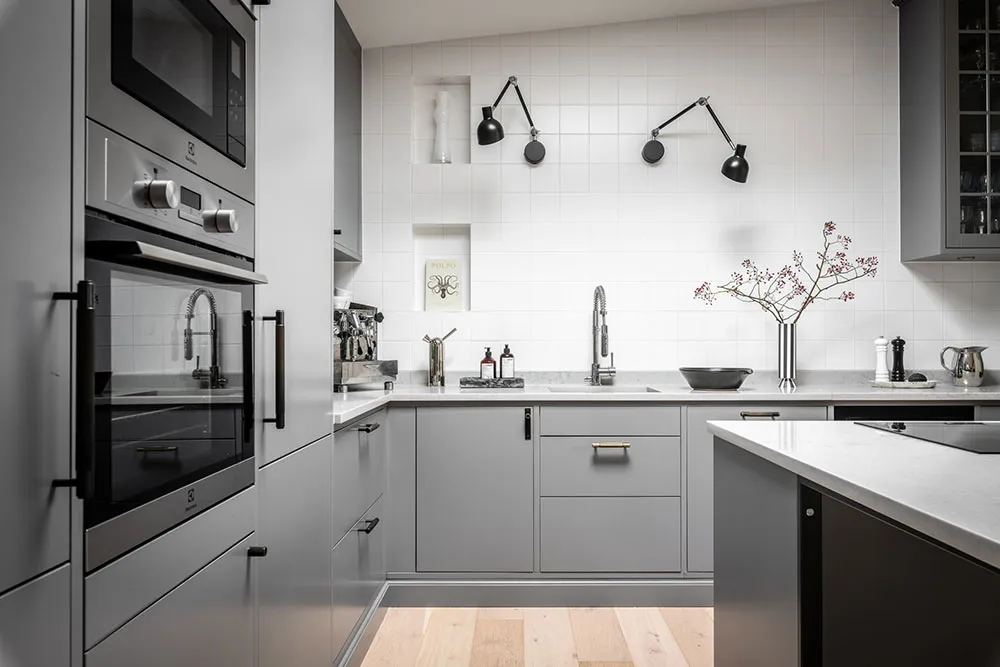 Modern minimalist kitchen with gray cabinets, white countertops, and white backsplash tiles.