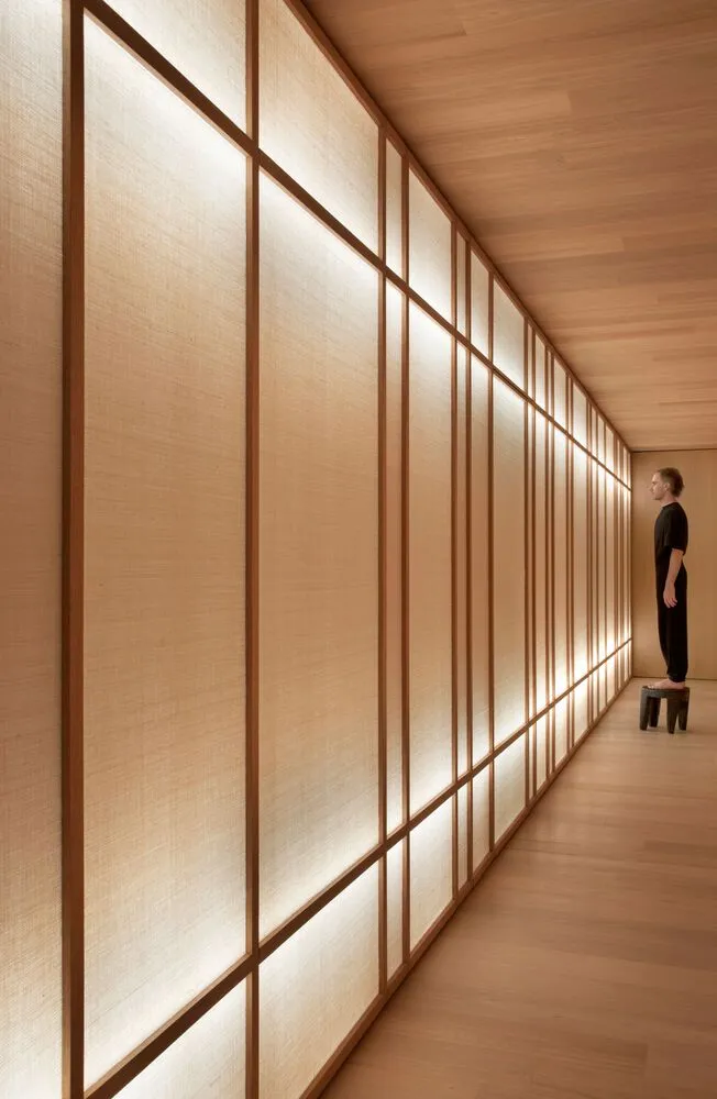 A minimalist interior space featuring modern wood paneled walls with soft lighting.