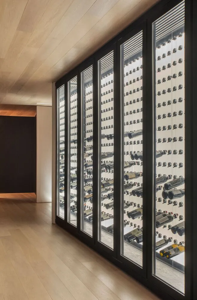 A modern wine cellar with glass doors filled with numerous bottles of wine.