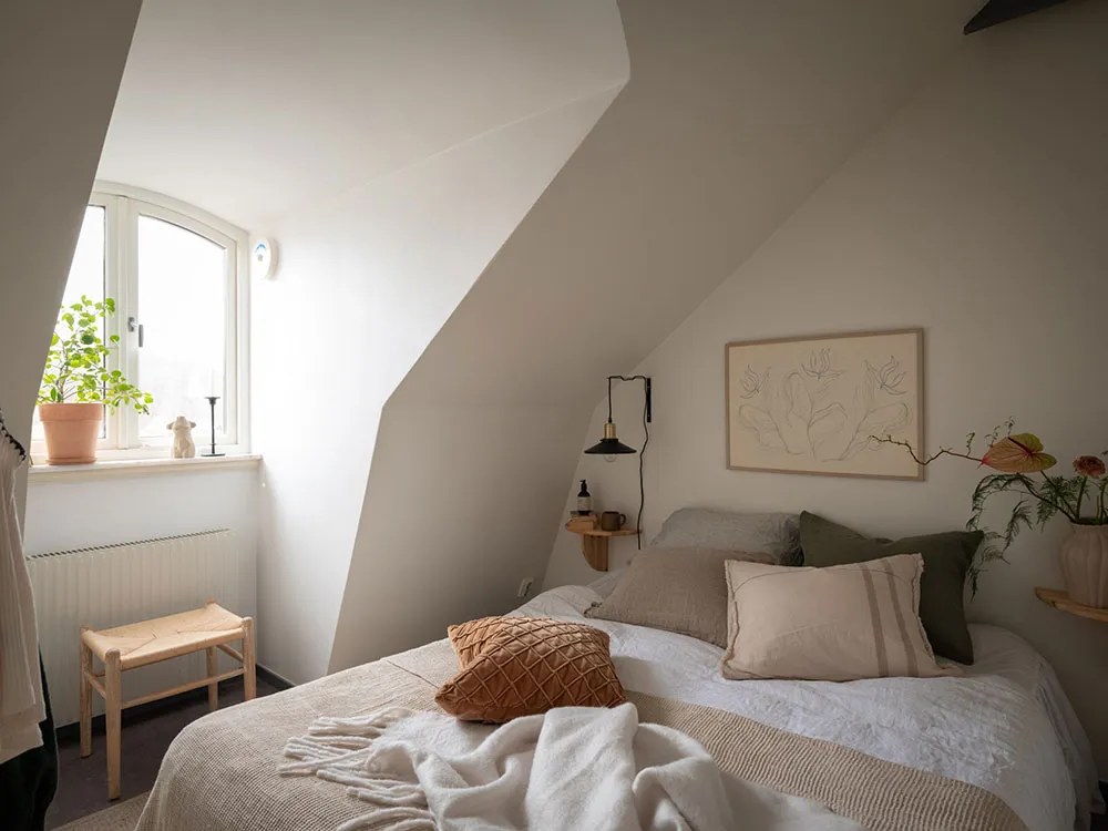 A minimalist bedroom with a bed, pillows, and a blanket.