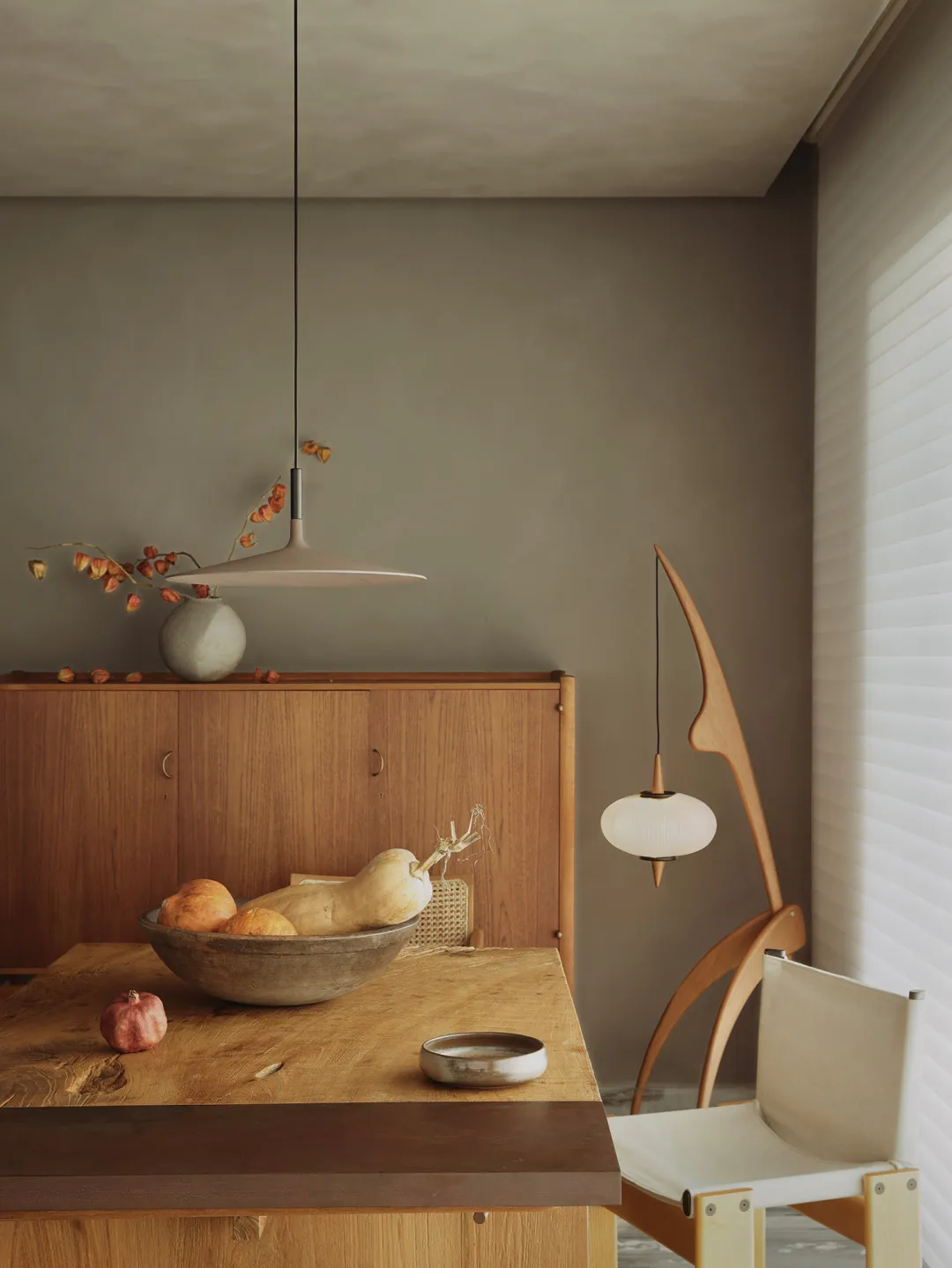 A small, minimalist interior with a wooden table, a potted plant, and a single white chair.