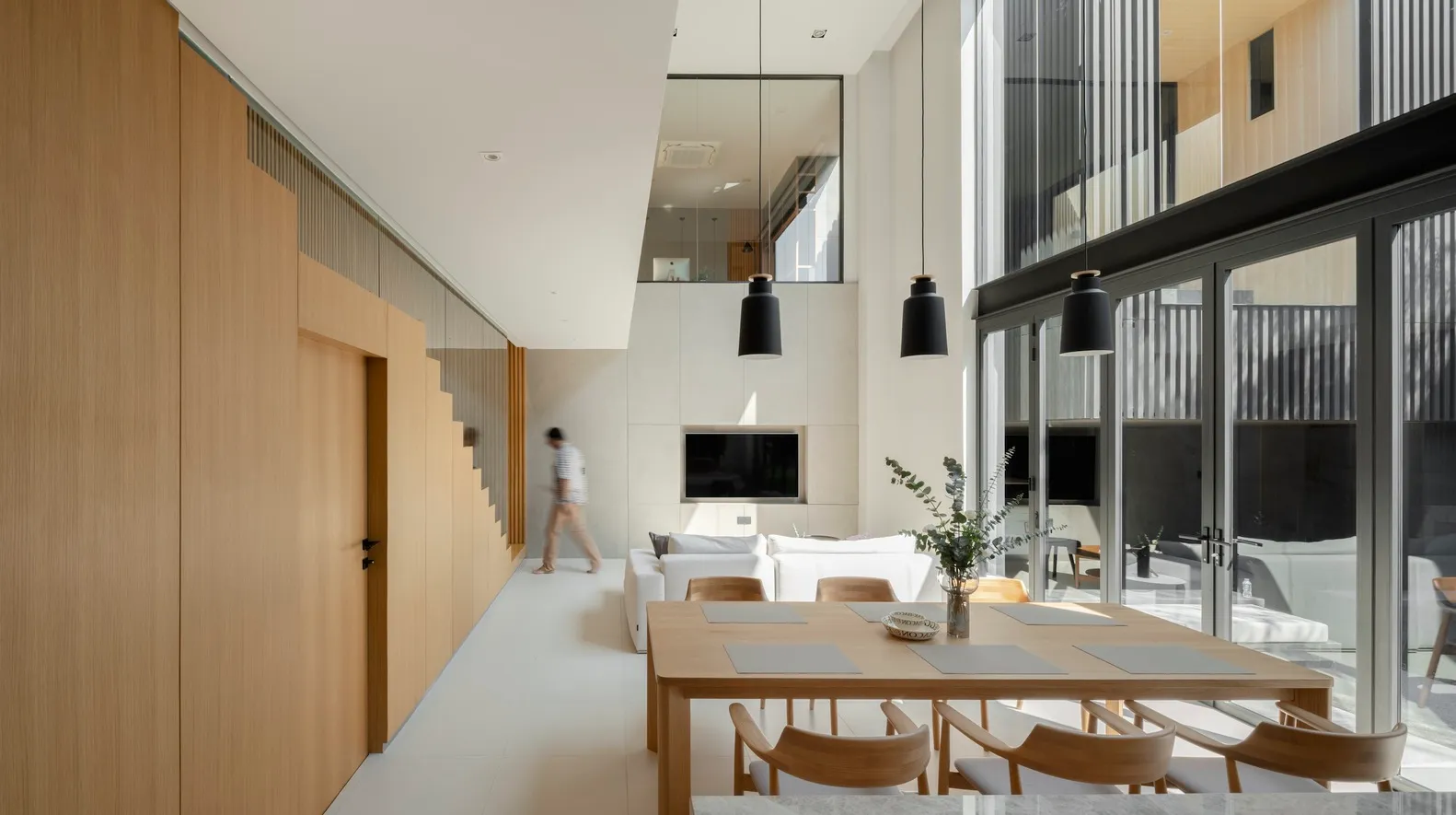 Modern living and dining space featuring a minimalist interior design with concrete and glass elements.