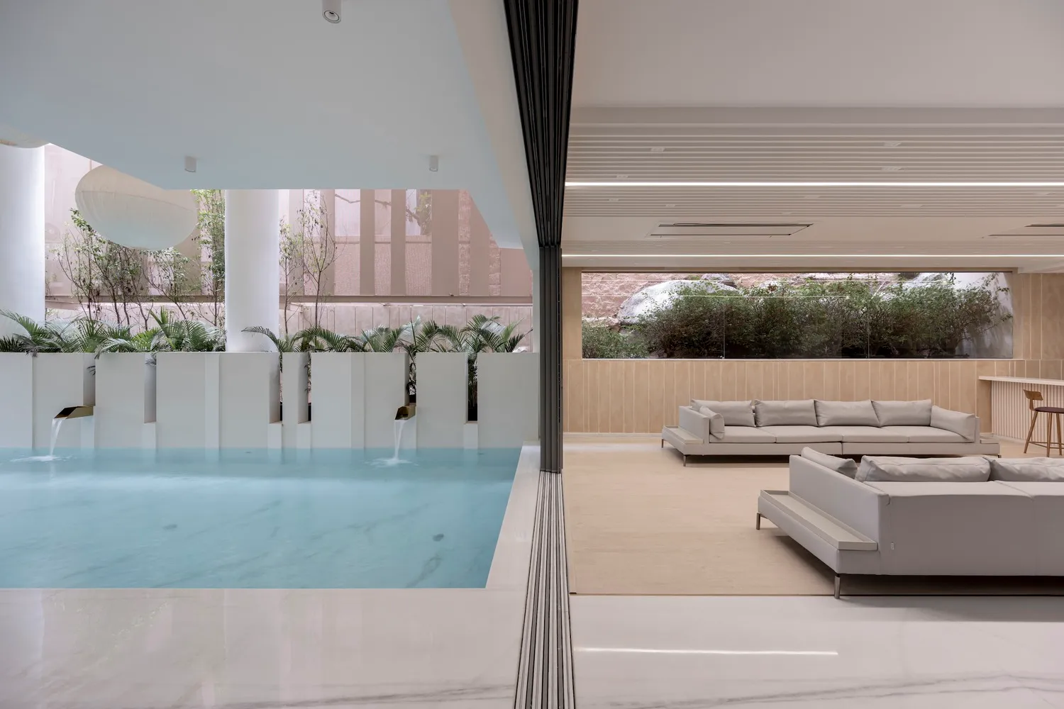 Modern minimalist living room with concrete walls, glass windows, and marble furniture.