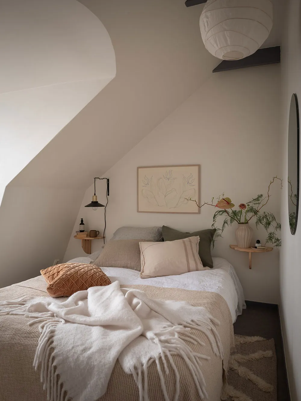 A cozy bedroom with a white bed, minimalist decor, and warm lighting.