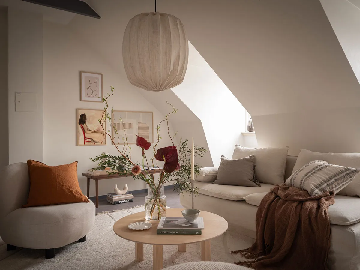 Modern minimalist living room with neutral tones, featuring a low-profile sofa, accent pillows, and a round coffee table.