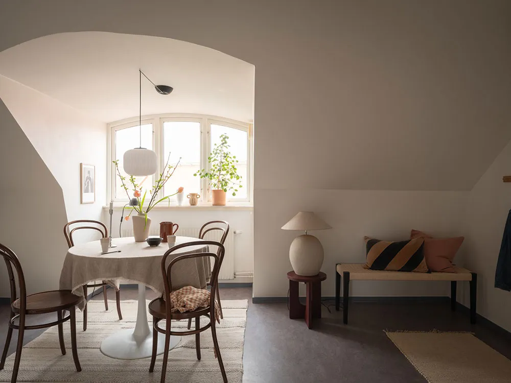 A modern minimalist dining room with wooden chairs, fabric tablecloth, and ceramic vases and cups on the table.