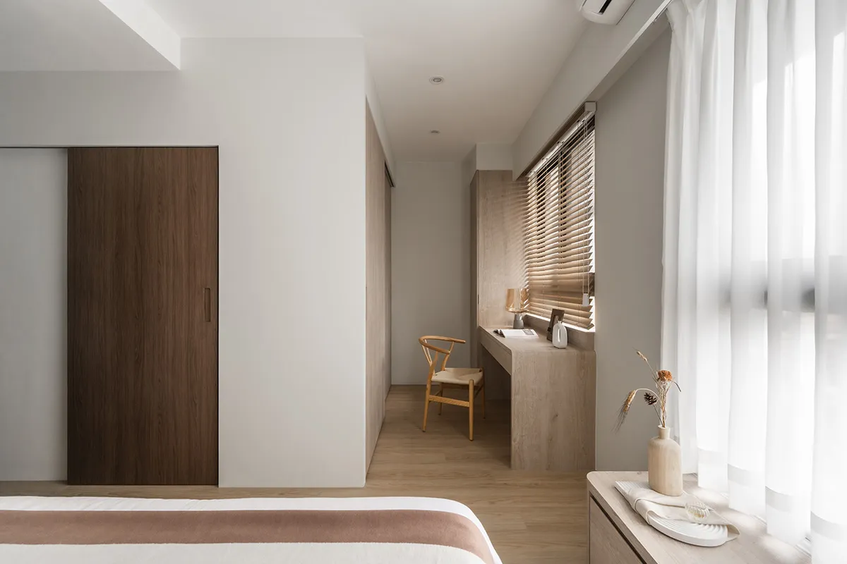 A minimalist bedroom featuring wooden furniture and materials, with soft lighting and a clean, uncluttered design.