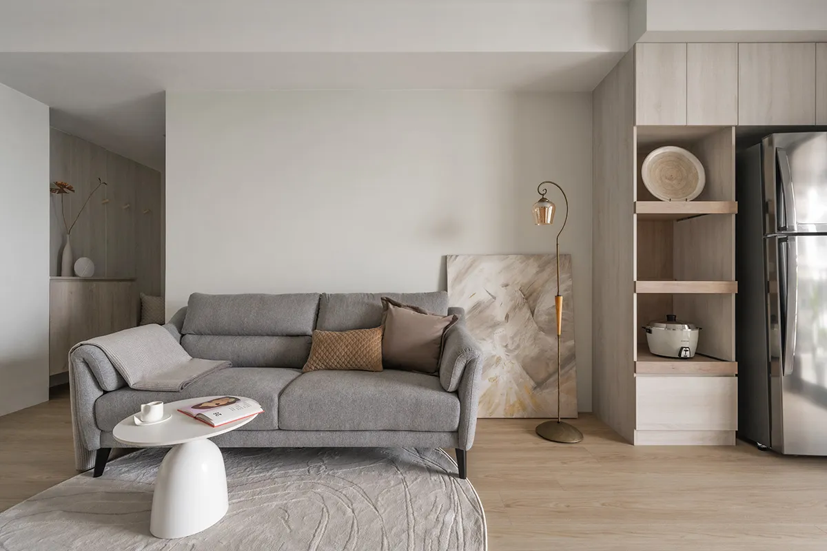 A minimalist living room with a gray couch adorned with cushions, a white coffee table, and a modern design aesthetic.