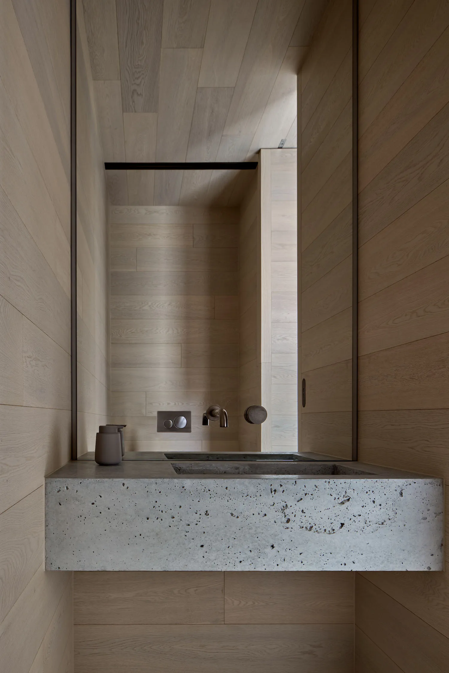A modern bathroom with concrete walls and a mirror above a sink.