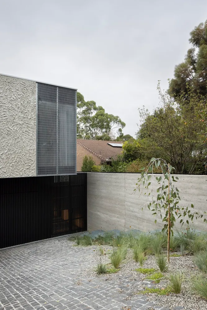 Modern exterior house extension made of concrete materials, featuring a grid-pattern design on the wall.