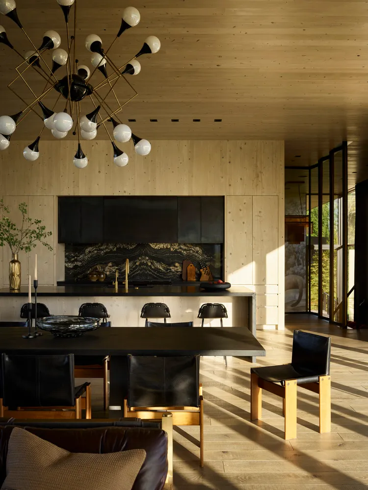 Contemporary residential kitchen dining area featuring wooden paneling and a black marble kitchen island.