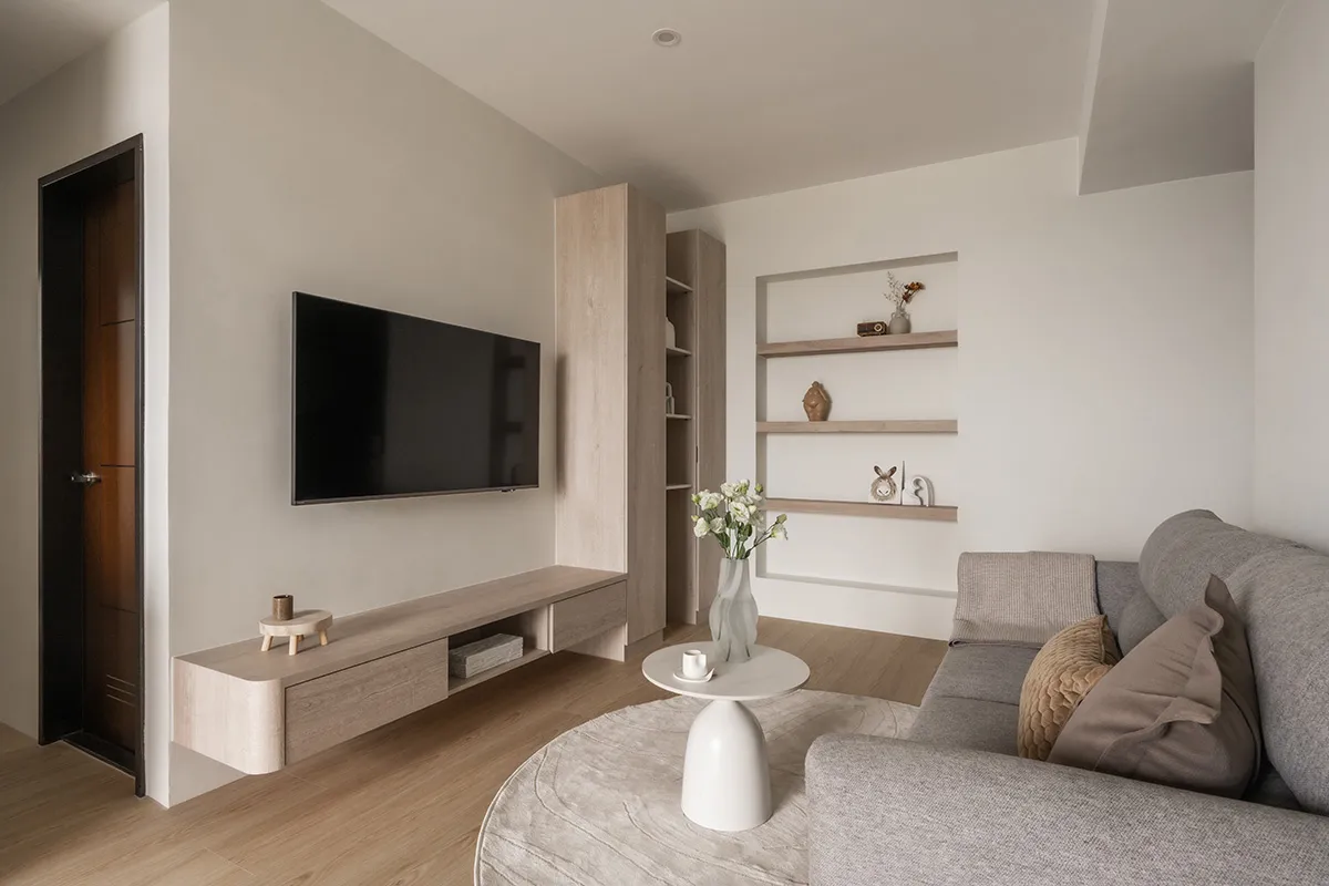 A modern living room featuring a floating wooden unit and light-colored furnishings.