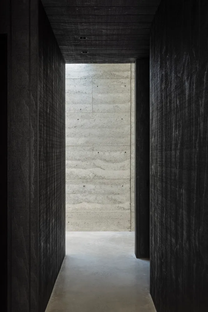 A minimalist interior with concrete walls and a hallway.