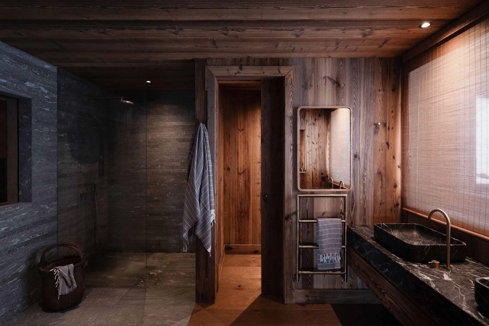 A modern, industrial-style bathroom with wooden walls, a stone sink, and a glass shower enclosure.