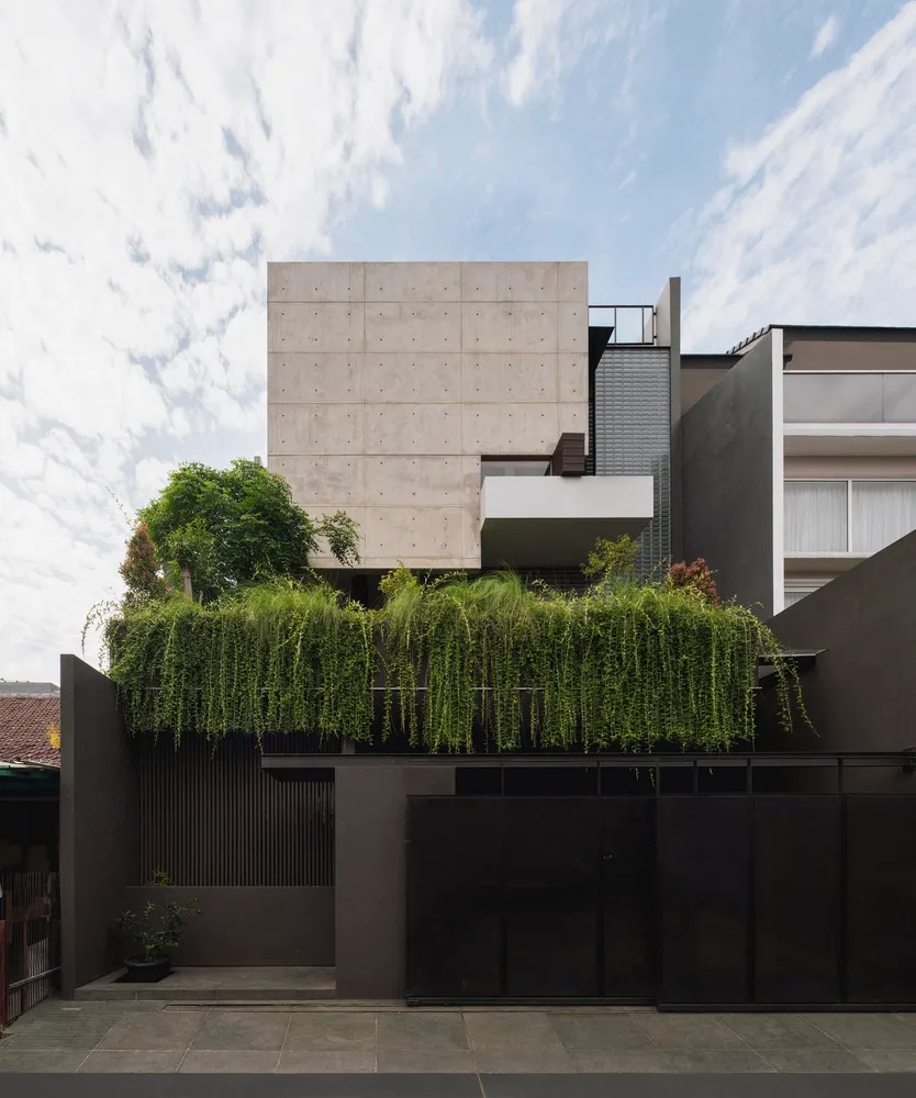 Modern, minimalist concrete house exterior with greenery on the rooftop.