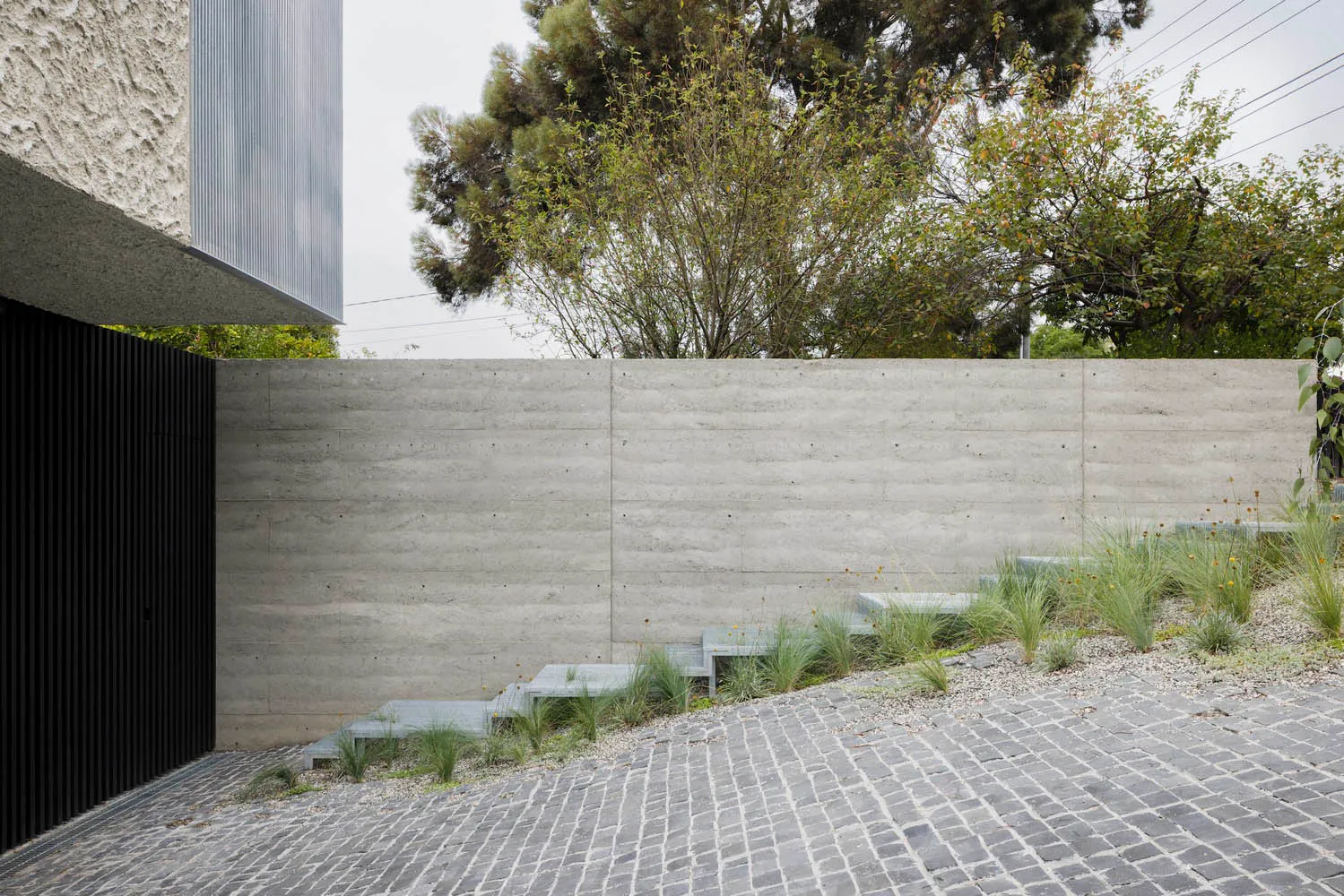 A modern landscape design featuring concrete paths, steps, and retaining walls surrounded by greenery.