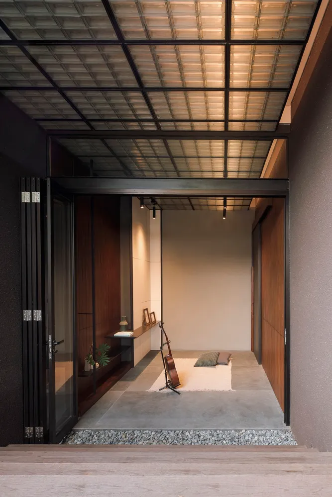 A minimalist living room with concrete flooring and wooden accents, featuring a single wooden floor lamp.