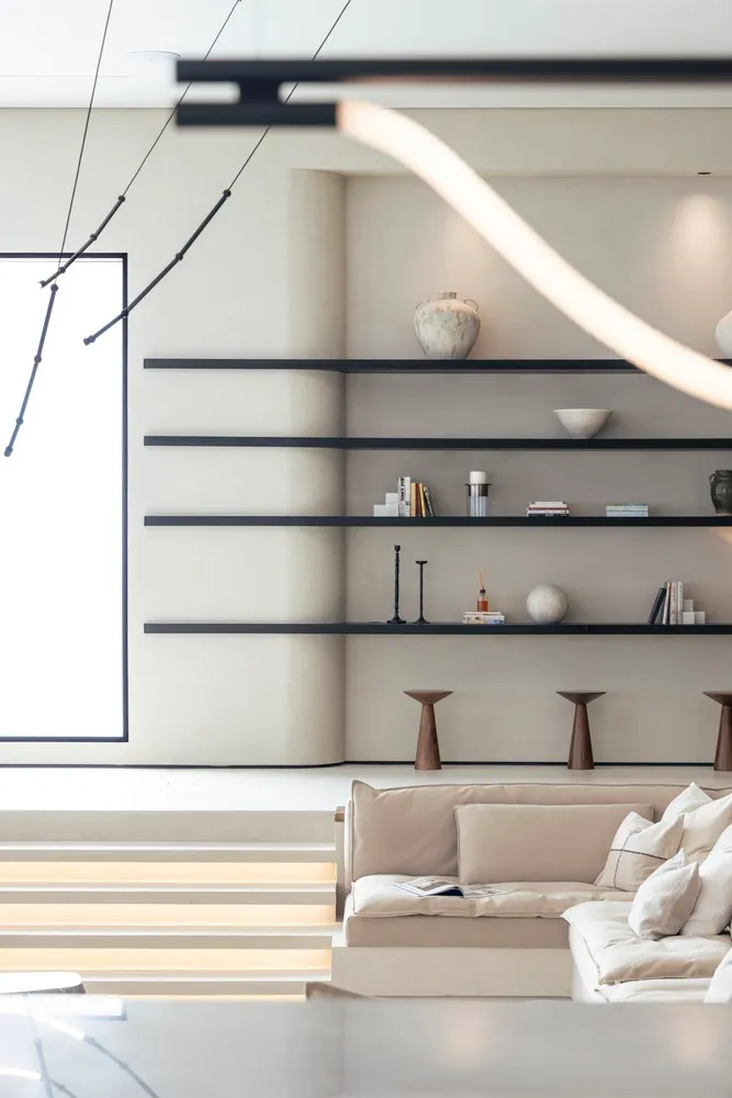 Minimalist living room with concrete furniture and floating shelves.