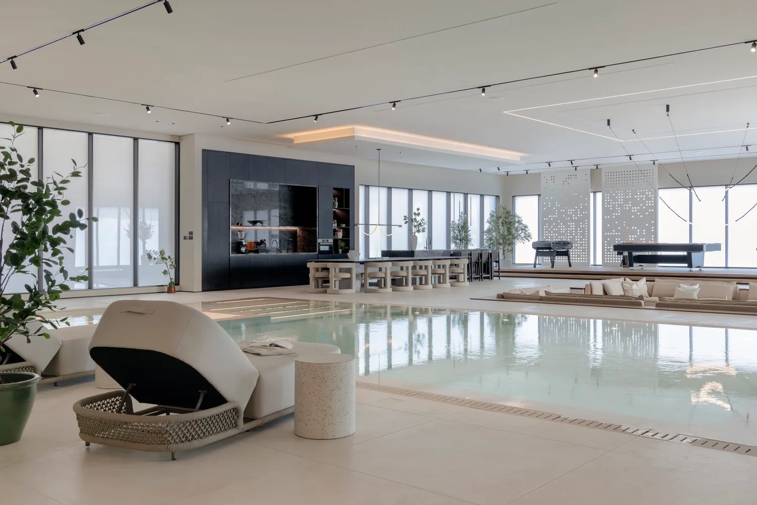 Modern minimalist living space featuring a swimming pool and concrete and glass architectural elements.