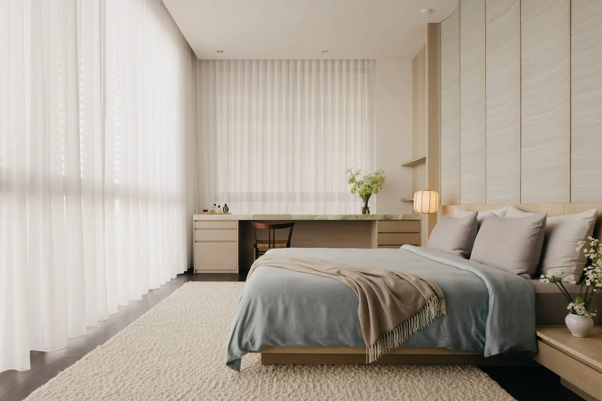 A minimalist bedroom featuring a white bed with light wood accents, a desk, and sheer curtains.