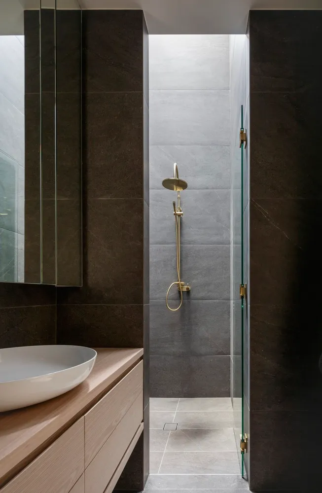 Modern minimalist black and gray bathroom shower space with ceramic tile walls.