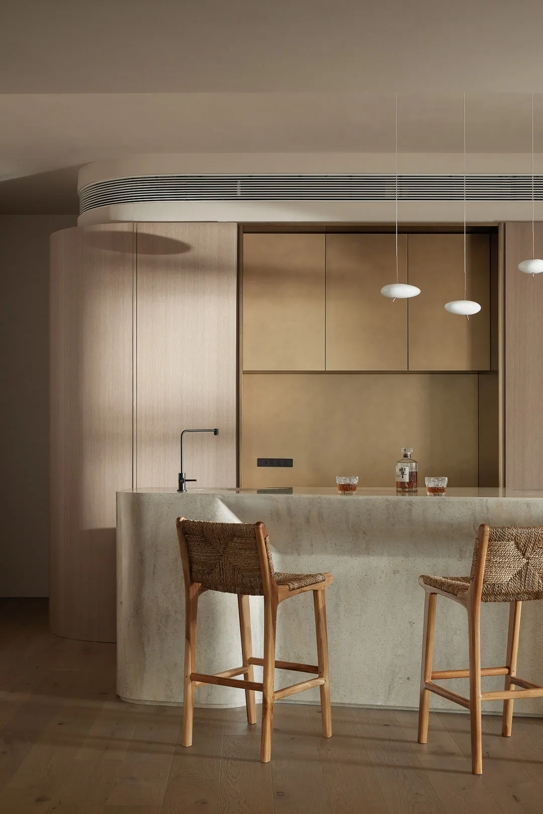 Modern, minimalist residential kitchen with concrete countertops and wooden stools.