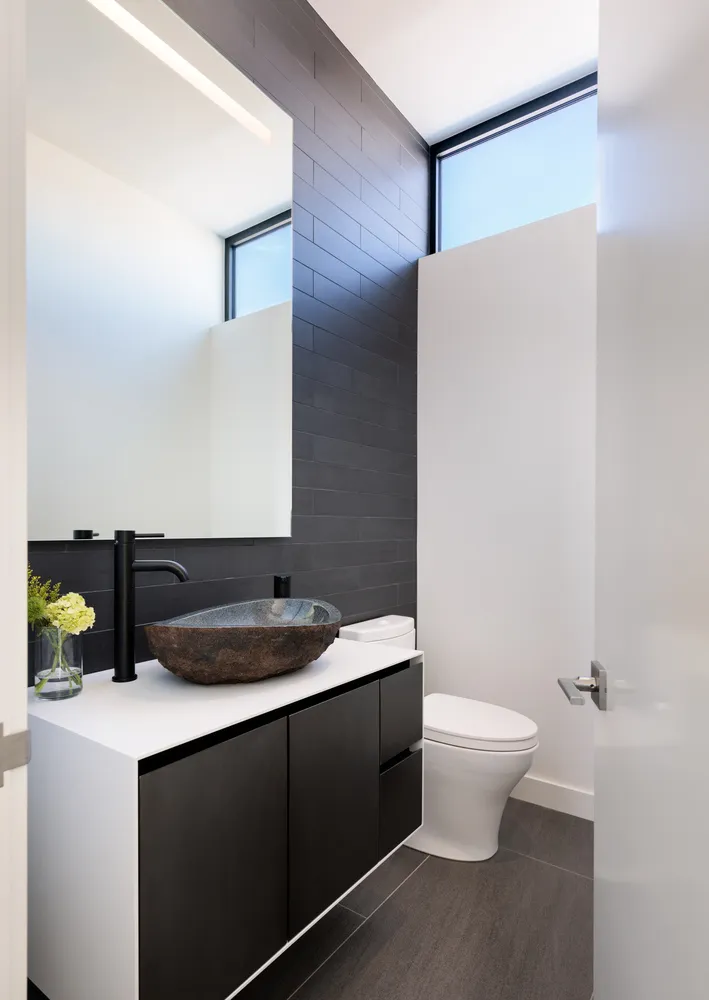 Modern bathroom with a black brick wall and concrete flooring.