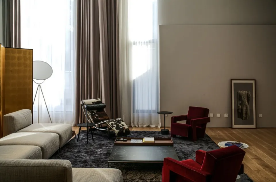 A modern living room featuring a mix of materials and textures, including a textured rug, wooden floor, and contemporary furn