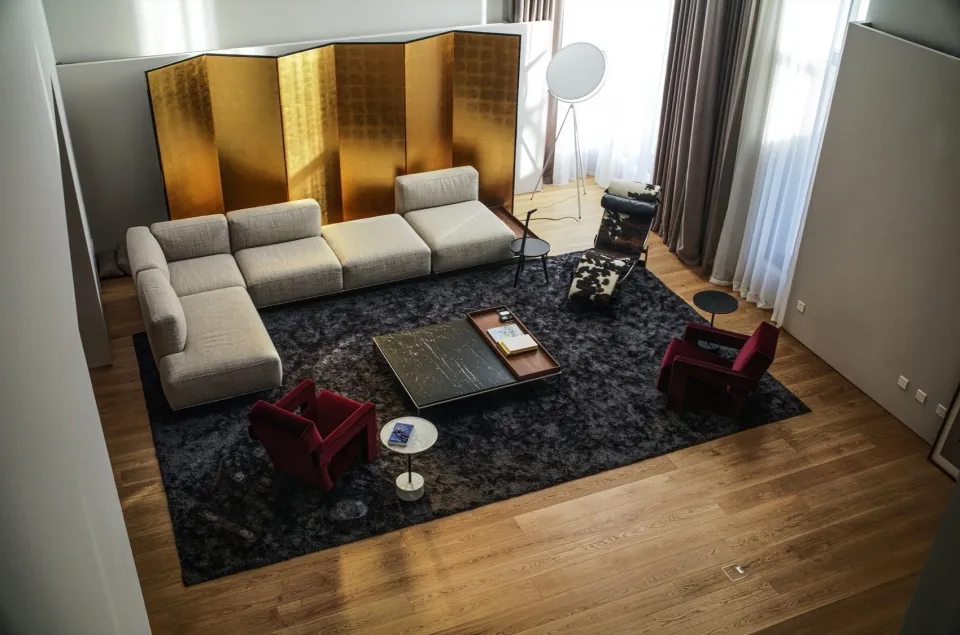 Modern living room featuring a comfortable sofa, armchairs, a coffee table, and a decorative copper screen.
